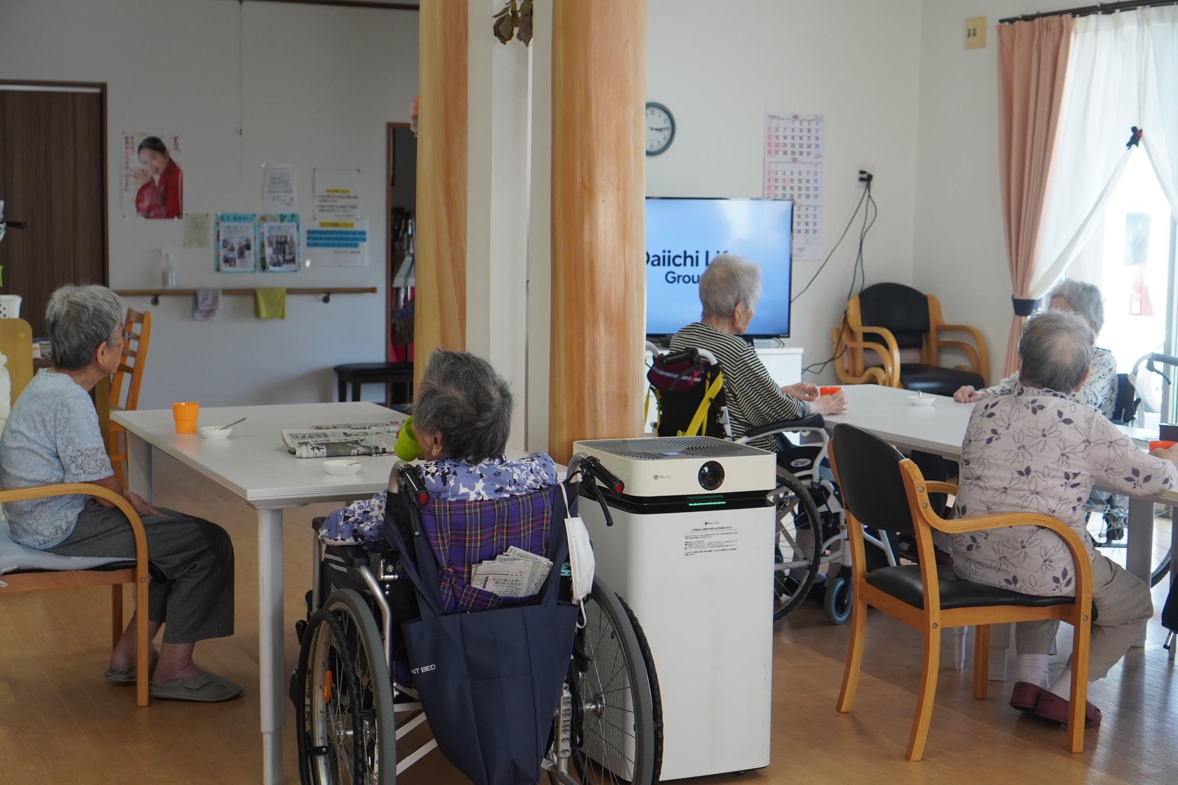 利用者がテーブルを囲んで過ごす明るいデイサービスの全景