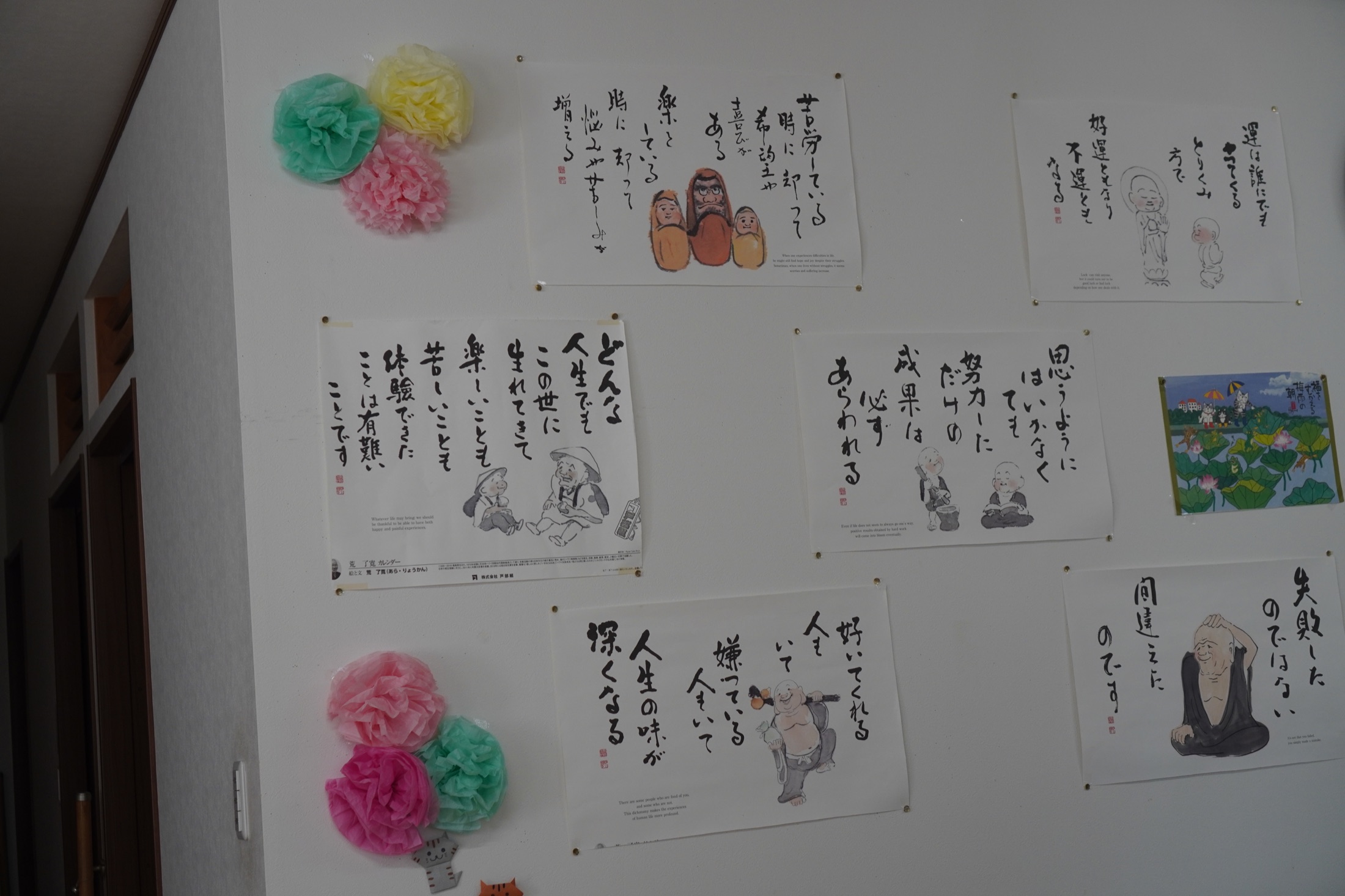 作品と季節の飾りが並ぶデイサービスの壁面