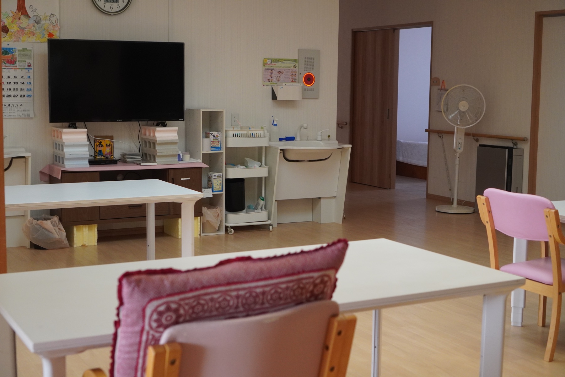 テレビや洗面設備とテーブルを備えた明るい共用空間